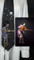 Black Prince Holding Guitar Sideways Dramatically While Performing Live in Purple Trench and Black Pants