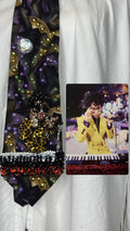 Purple Gold, and Green Marbled Prince in Full Yellow Polka Dot Suit Playing on Orange Cheetah Print Piano Live Tie